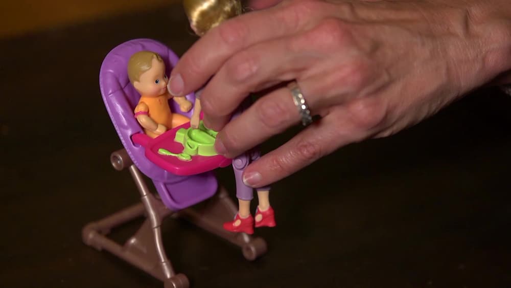 A hand holding on to a small child's plastic bay doll toy