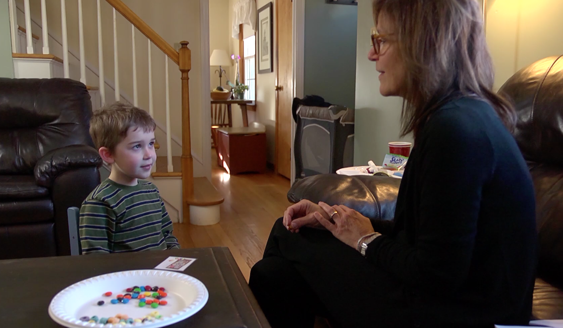 A teacher and a child sitting together in a living room