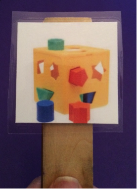 A picture of a toy taped to a block of wood