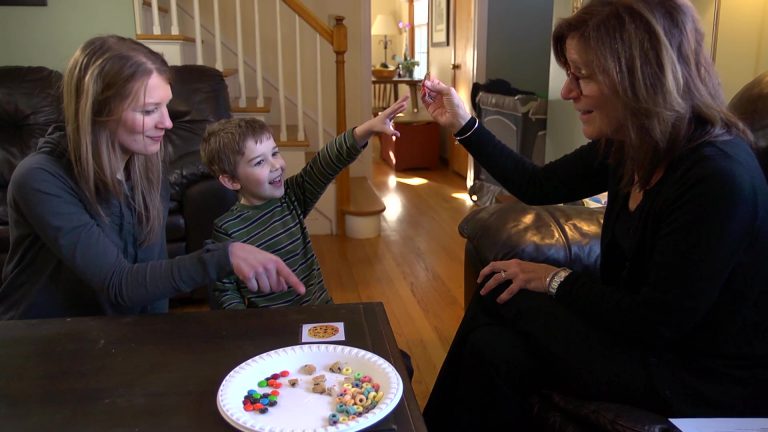 A child pointing to some candies that his mother is holding up